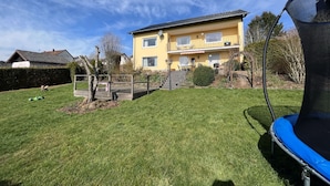 A two-story house with a balcony, a trampoline, and a well-maintained lawn.
