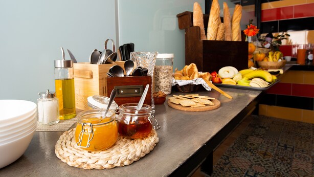 A breakfast buffet with bread, fruits, and condiments.
