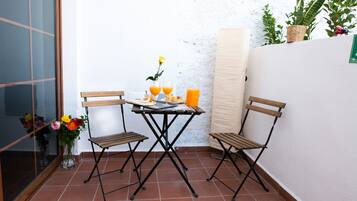 Ein kleiner Patio-Bereich mit Tisch und zwei Stühlen, einer Blumenvase und einem Blumentopf.