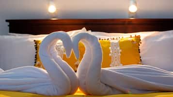 Una cama con una toalla dispuesta en forma de corazón y un cabecero de madera.