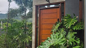 Un edificio moderno con puerta de madera, rodeado de exuberante vegetación tropical.