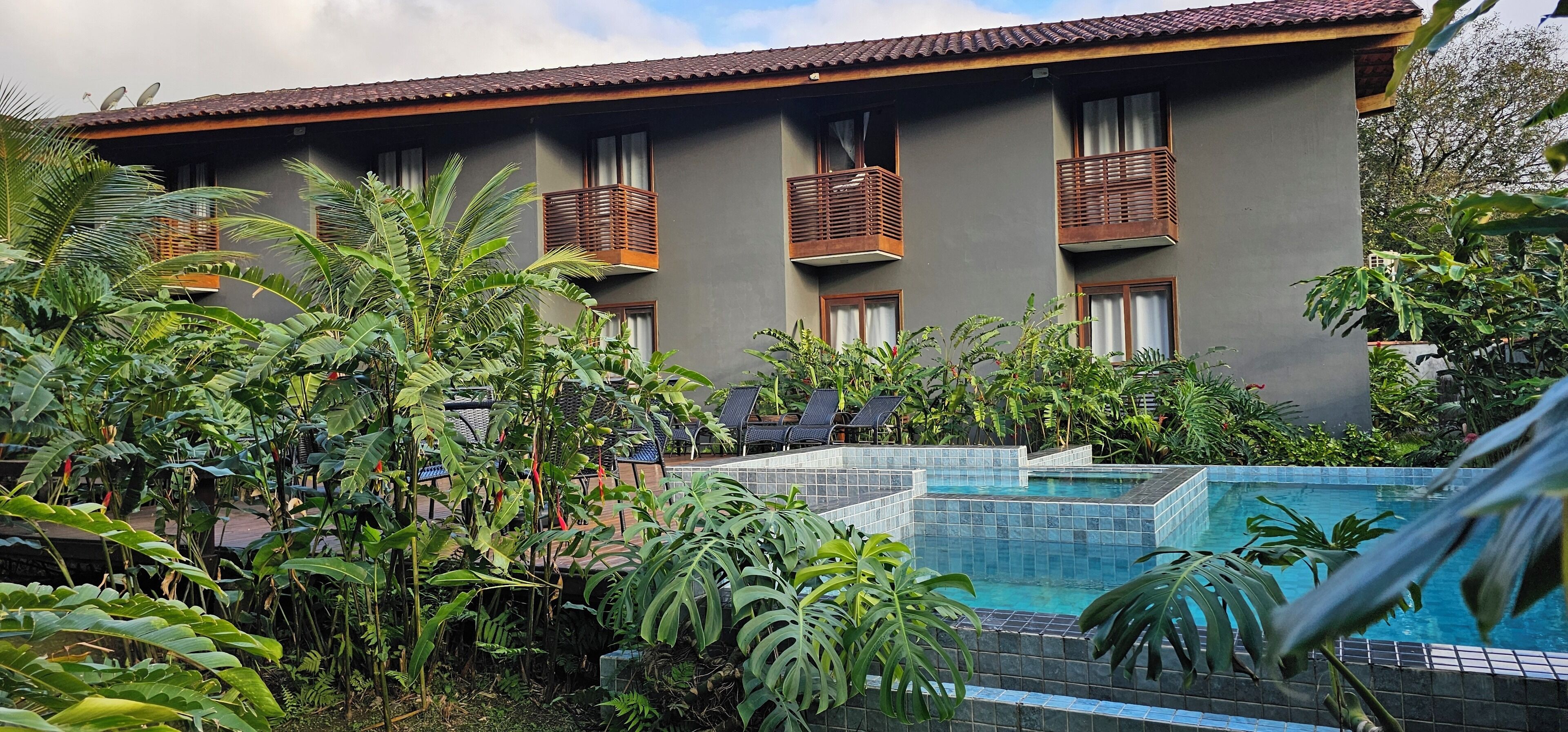 A hotel with a pool surrounded by lush tropical plants.
