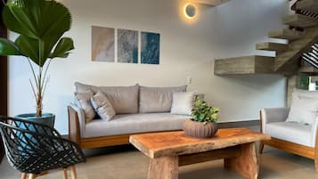 Een moderne woonkamer met een bank, twee stoelen, een salontafel en een trap.