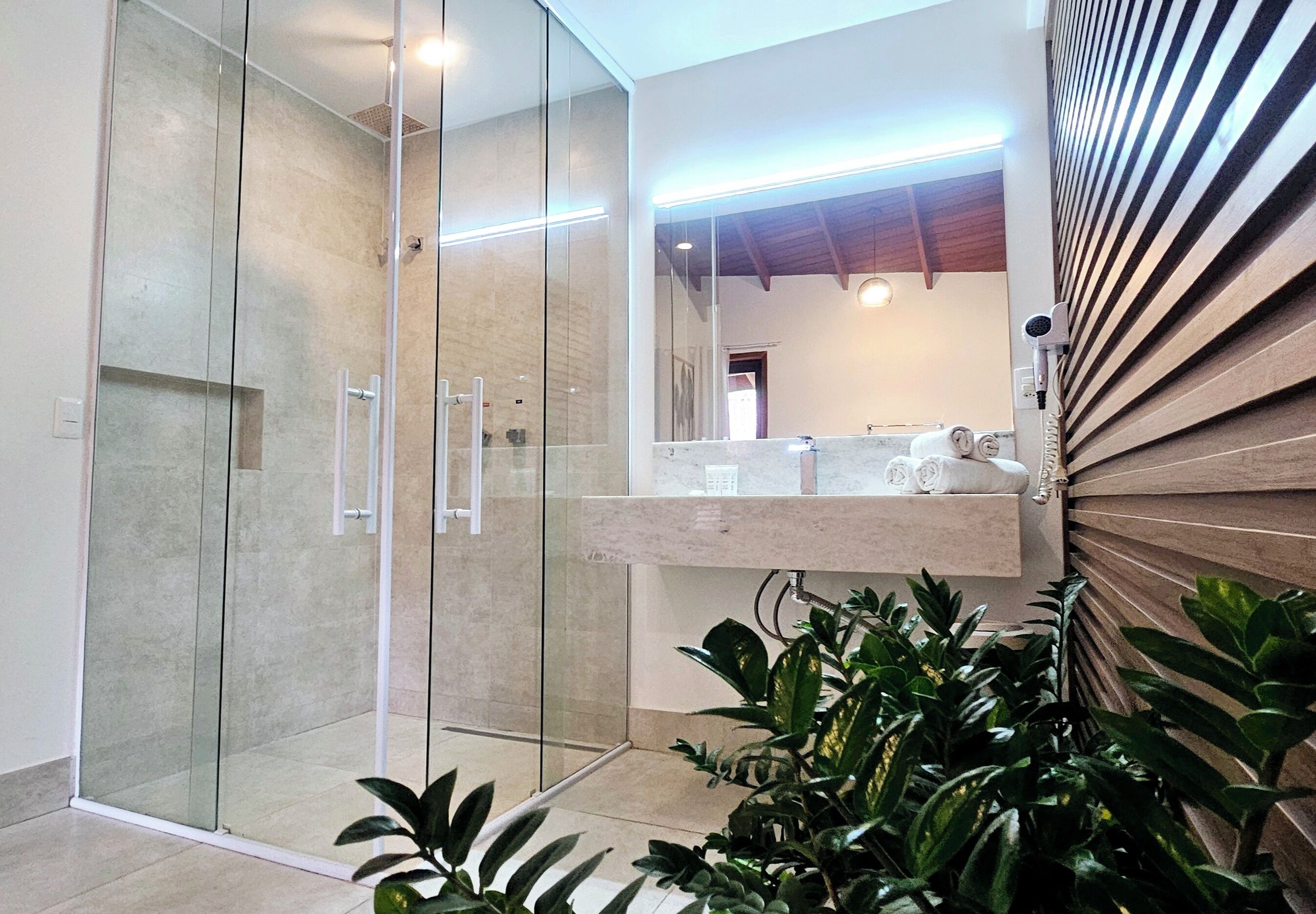 Une salle de bain moderne avec une douche à l’italienne en verre, un comptoir en marbre et un mur recouvert de panneaux en bois.