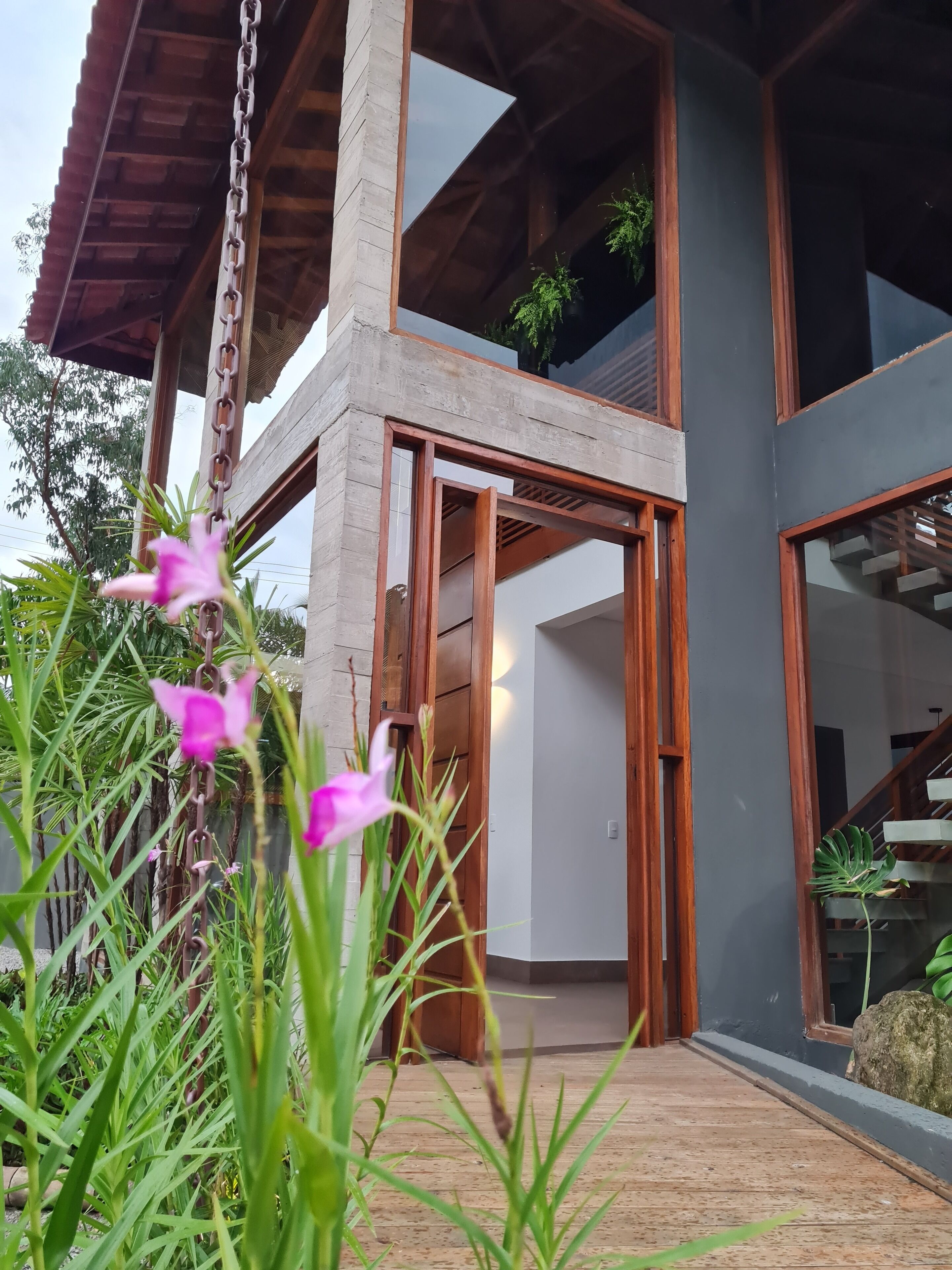 Un edificio moderno con fachada de hormigón, amplias ventanas y una escalera de madera.
