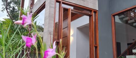 Un edificio moderno con fachada de hormigón, amplias ventanas y una escalera de madera.