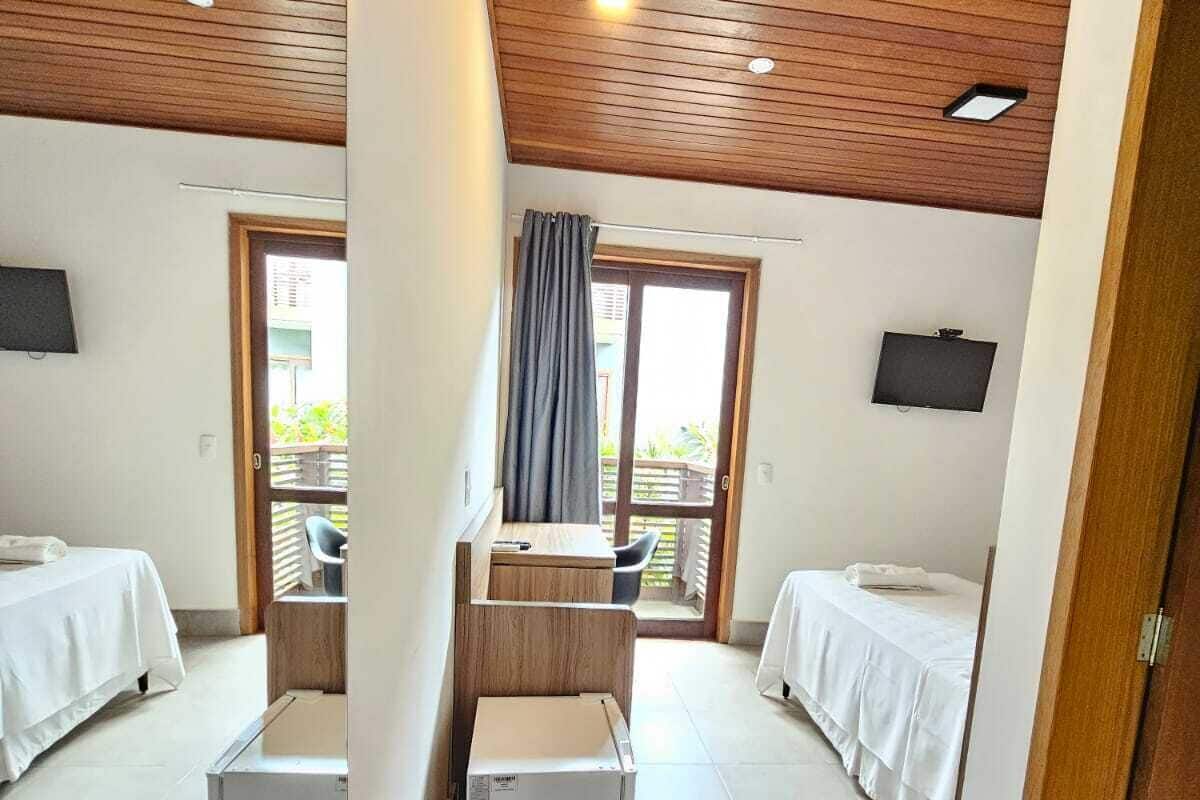 Habitación de hotel con dos camas, una kitchenette pequeña, un televisor y vistas al balcón.