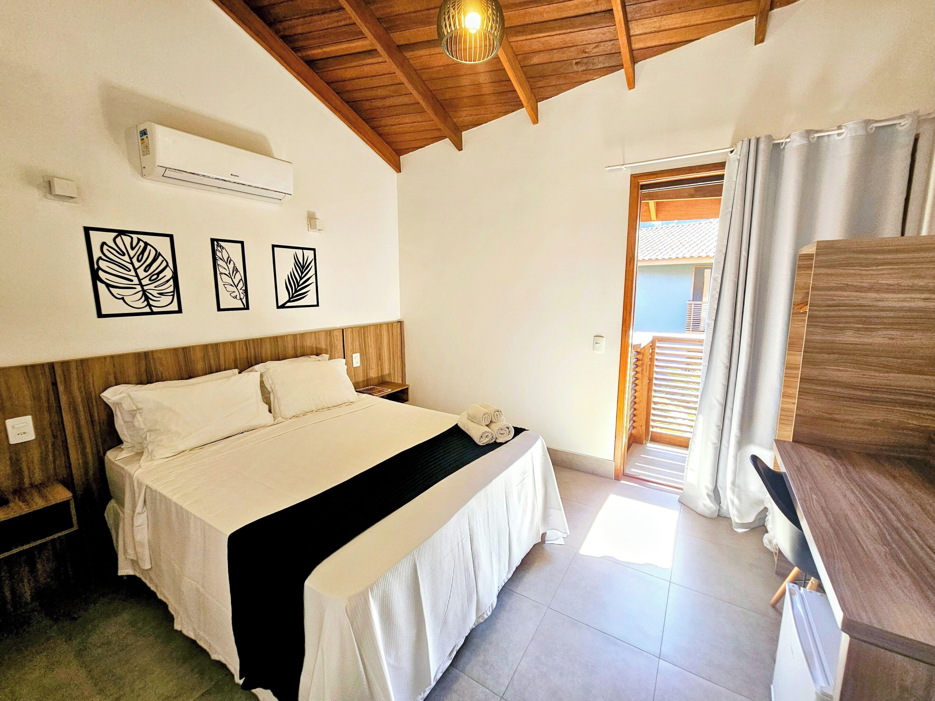Een slaapkamer met een bed, nachtkastjes, een airconditioning en uitzicht op het buiten.