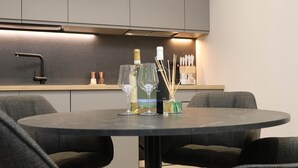 Una cocina moderna con una mesa redonda, dos sillas y una botella de vino.