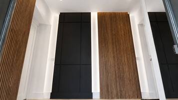 A modern interior with a high ceiling, recessed lighting, and a combination of black and wooden paneling on the walls.