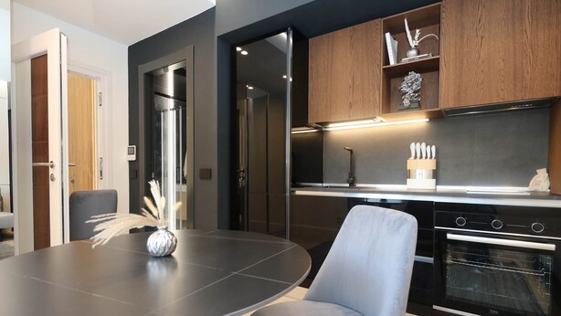 A modern kitchen with a built-in oven, a dining table with chairs, and a decorative vase. - Hidden GEM- luxurious holiday STUDIO Garibaldi-for couples (Olbia)