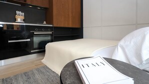 A modern kitchen with wooden cabinets, a black stove, and a countertop with kitchen utensils. - Hidden GEM- luxurious holiday STUDIO Garibaldi-for couples (Olbia)
