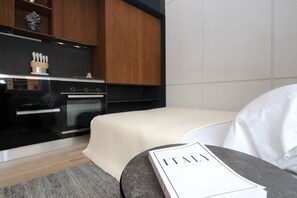 A modern kitchen with wooden cabinets, a black stove, and a countertop with kitchen utensils. - Hidden GEM- luxurious holiday STUDIO Garibaldi-for couples (Olbia)