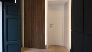 A hallway with a wooden panel wall, a white door, and a dark-colored cabinet. - Hidden GEM- luxurious holiday STUDIO Garibaldi-for couples (Olbia)