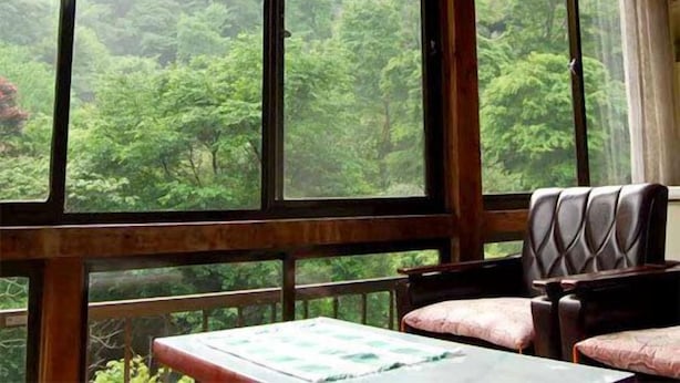 Una habitación con ventanas amplias, una mesa y dos sillas.