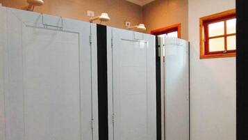 A hallway with four white doors, each with a black vertical stripe. There are ceiling lights and a window with wooden frames on the right wall.