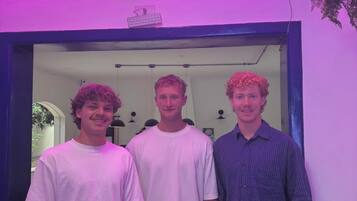 Three individuals standing in front of a neon sign that reads 'Welcome to São Paulo.'