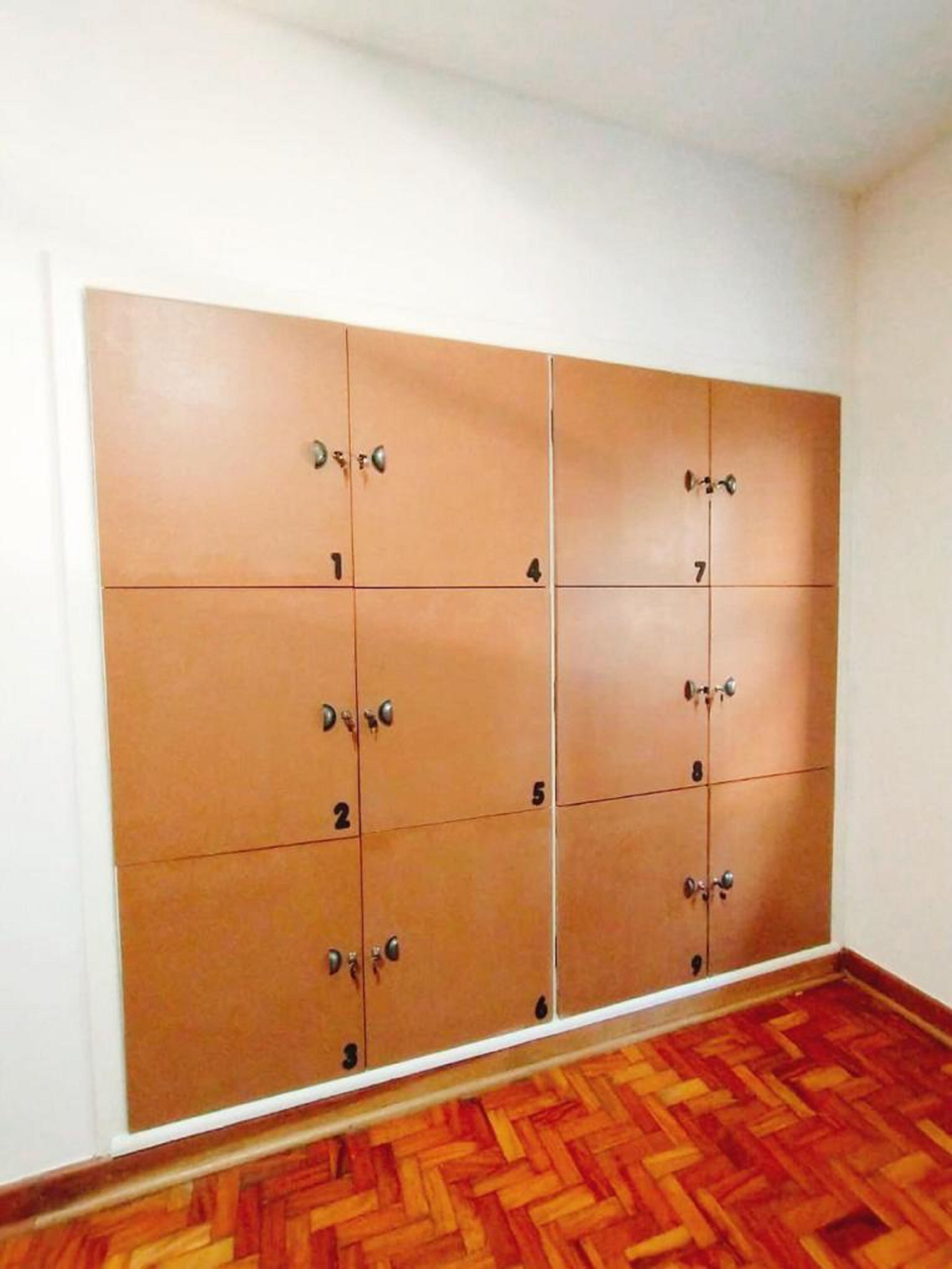 Una habitación con un amplio armario de madera con varios compartimentos, cada uno marcado con un número.