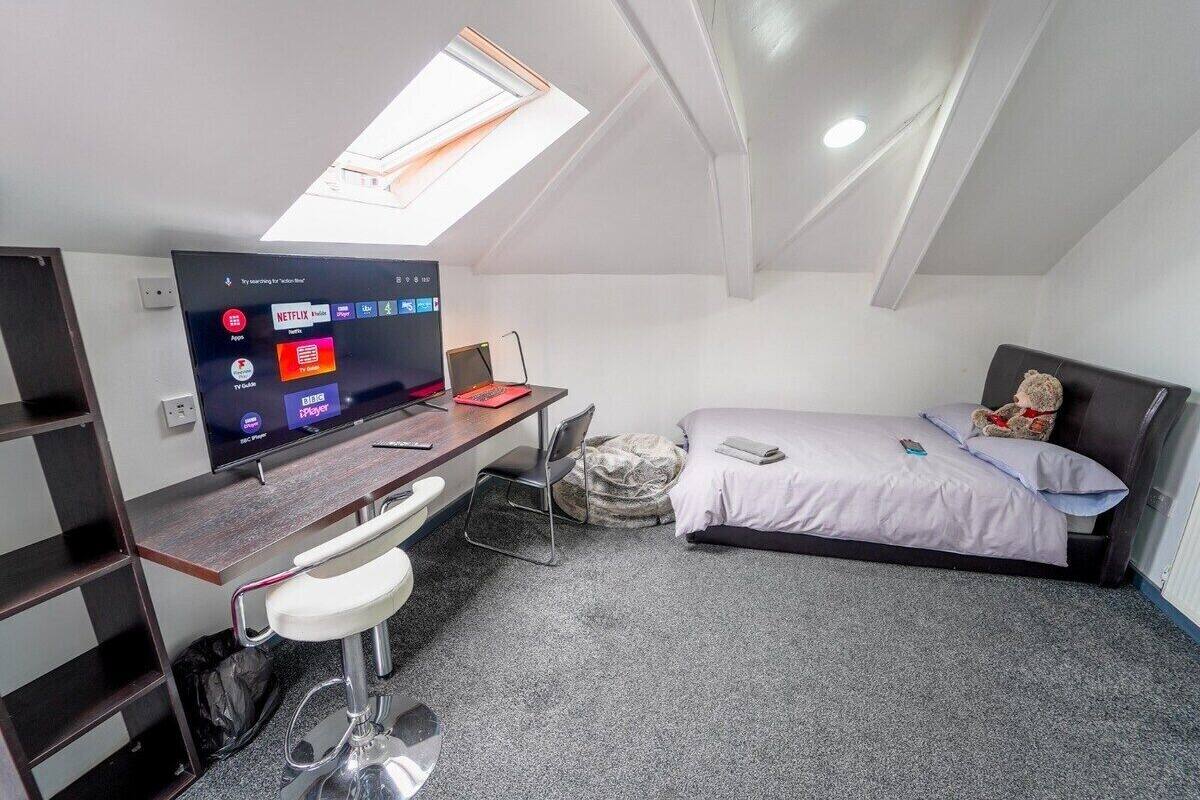 Une petite pièce comprenant un lit, un bureau avec un ordinateur, une chaise et un téléviseur permettant d’accéder à des services de diffusion en continu.