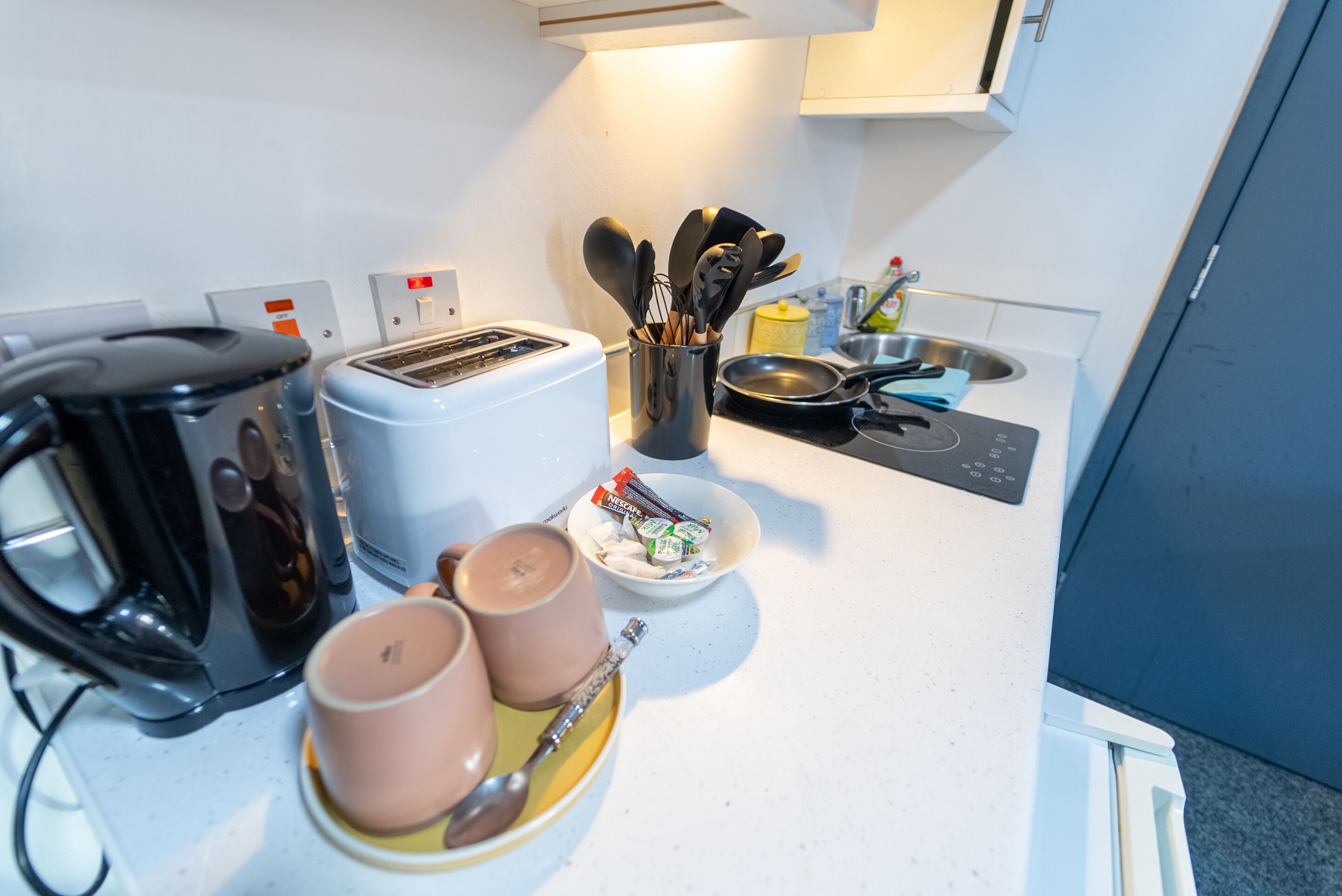 Une petite cuisine équipée d’un grille-pain, d’une machine à café et d’ustensiles de cuisine.