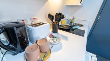 Une petite cuisine équipée d’un grille-pain, d’une machine à café et d’ustensiles de cuisine.