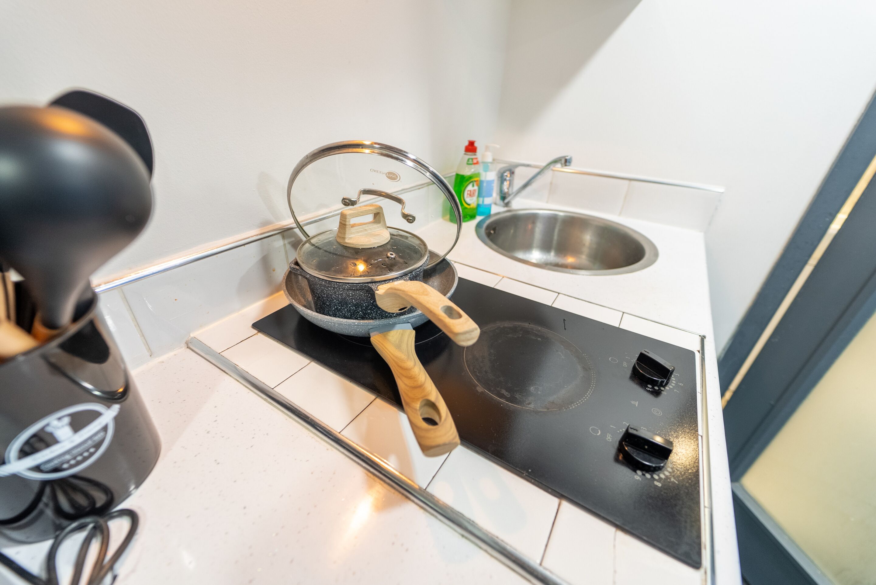 A kitchen with a stove, a kettle, and a sink.
