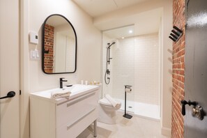 Une salle de bain moderne avec un meuble-lavabo blanc, des toilettes, une douche et un miroir.