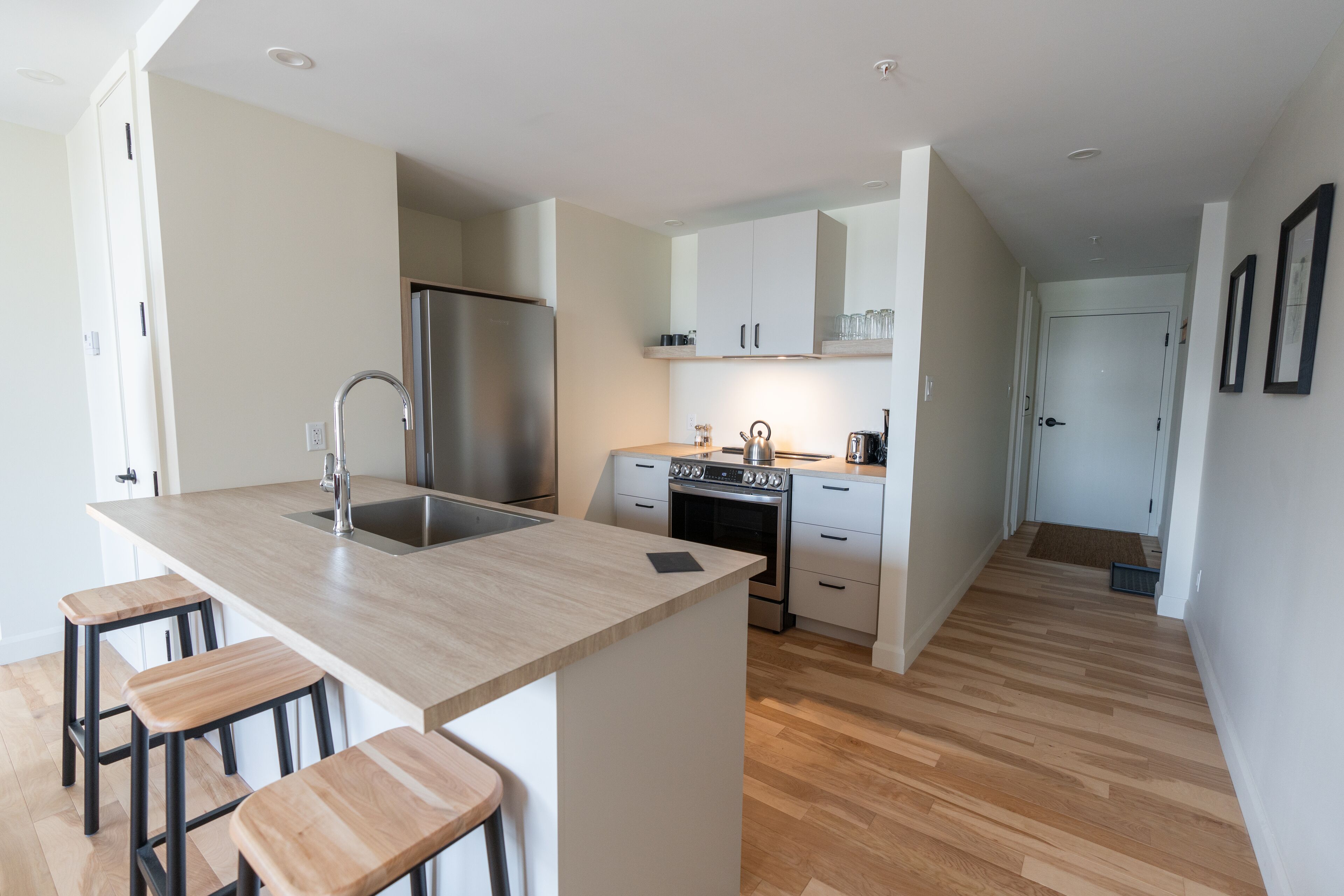 A modern kitchen with a central island, stainless steel appliances, and wooden flooring.