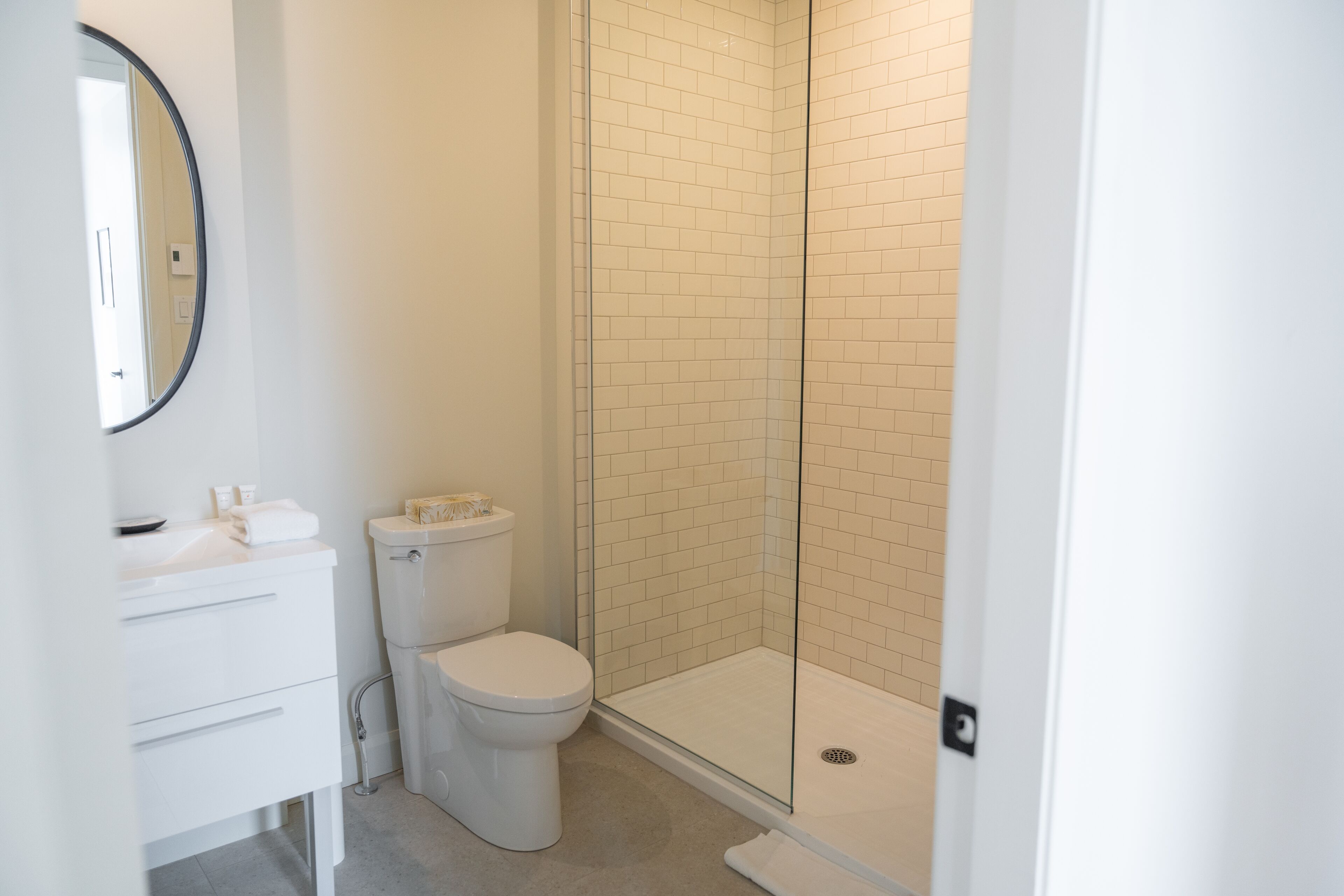 Une salle de bain comprenant des toilettes, un lavabo et une douche séparée par une paroi en verre.