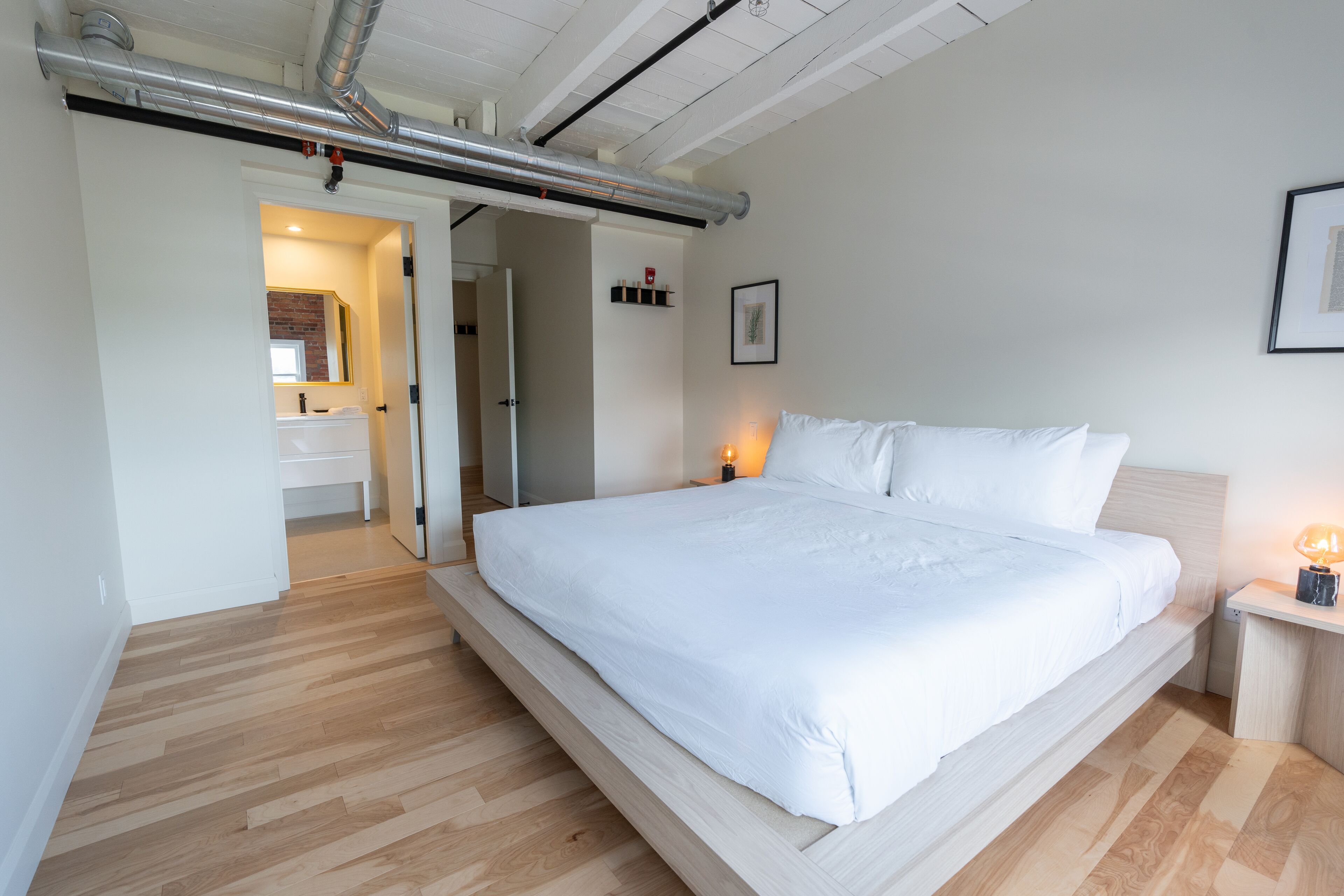 Una camera da letto con un letto grande, un comodino con una lampada e una porta che dà su un bagno.