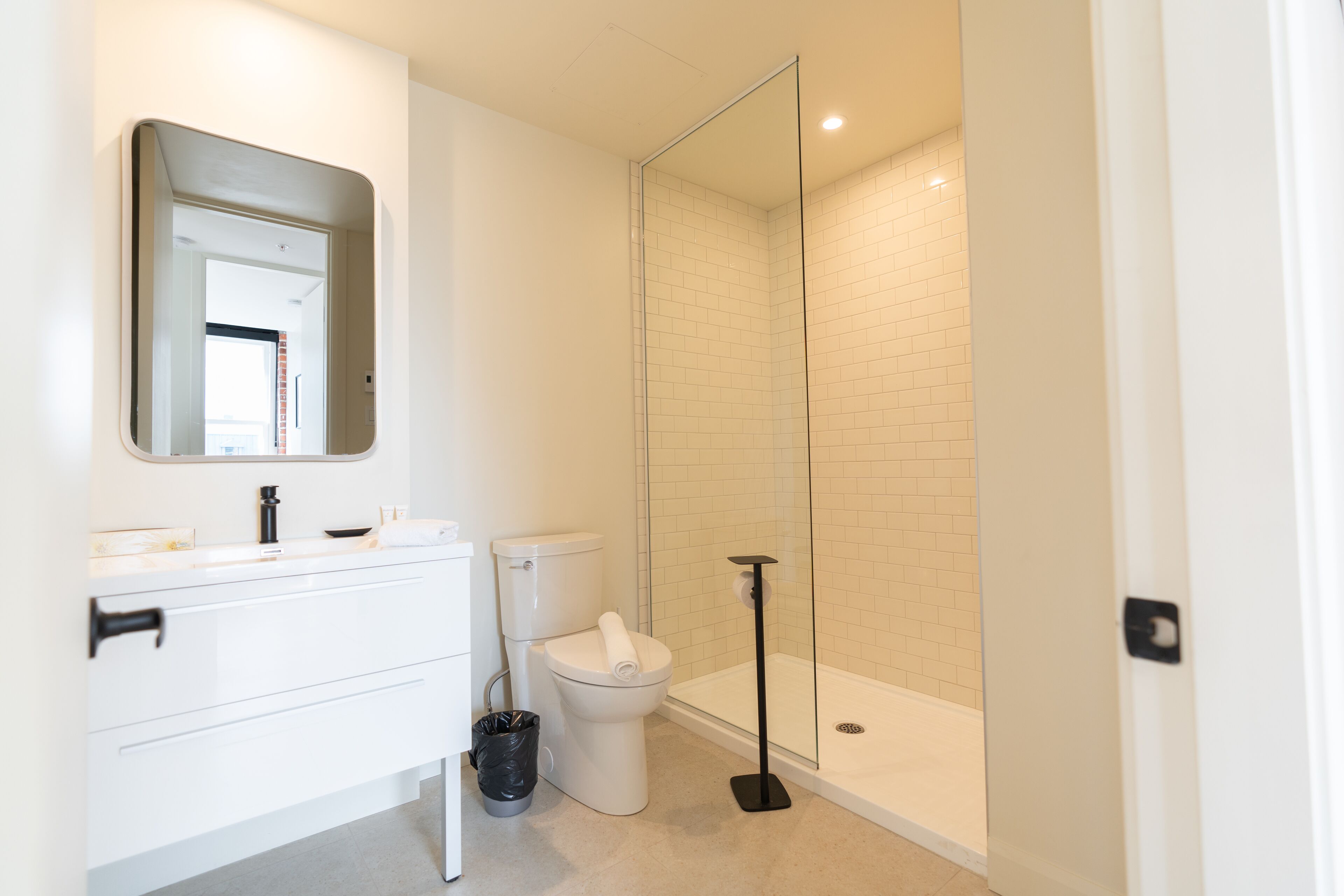 A bathroom with a white vanity, toilet, and glass-enclosed shower.