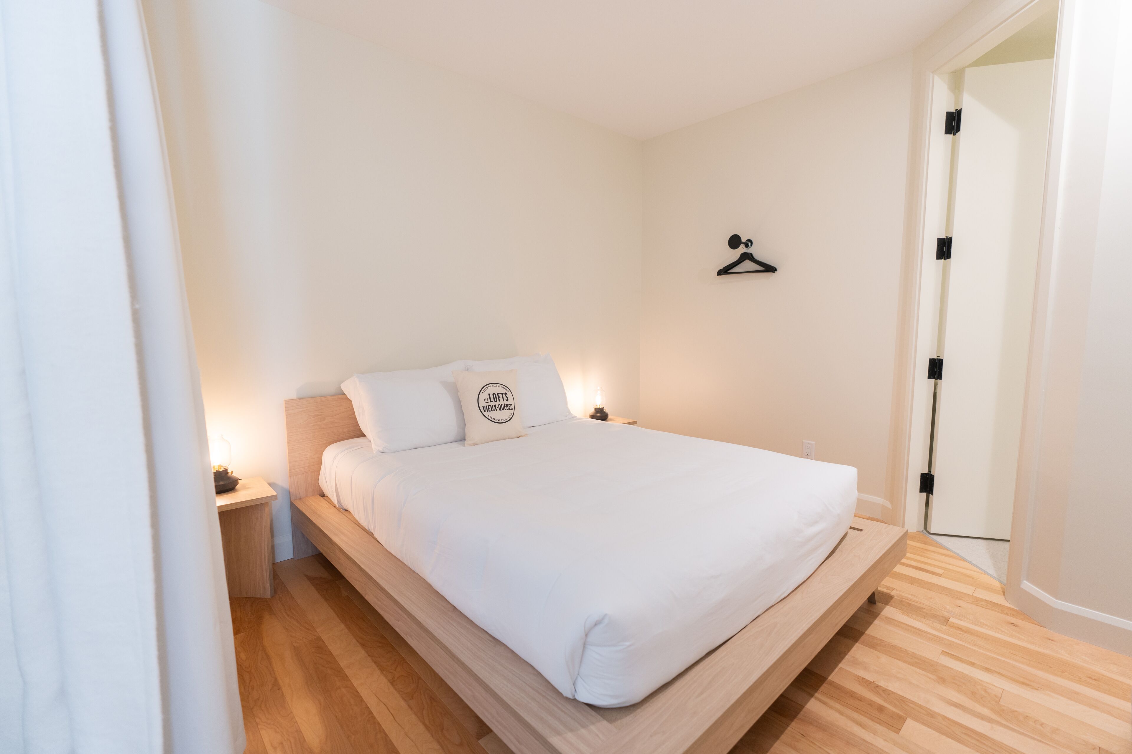 A minimalist bedroom with a single bed, a bedside table, and a wall-mounted hanger.