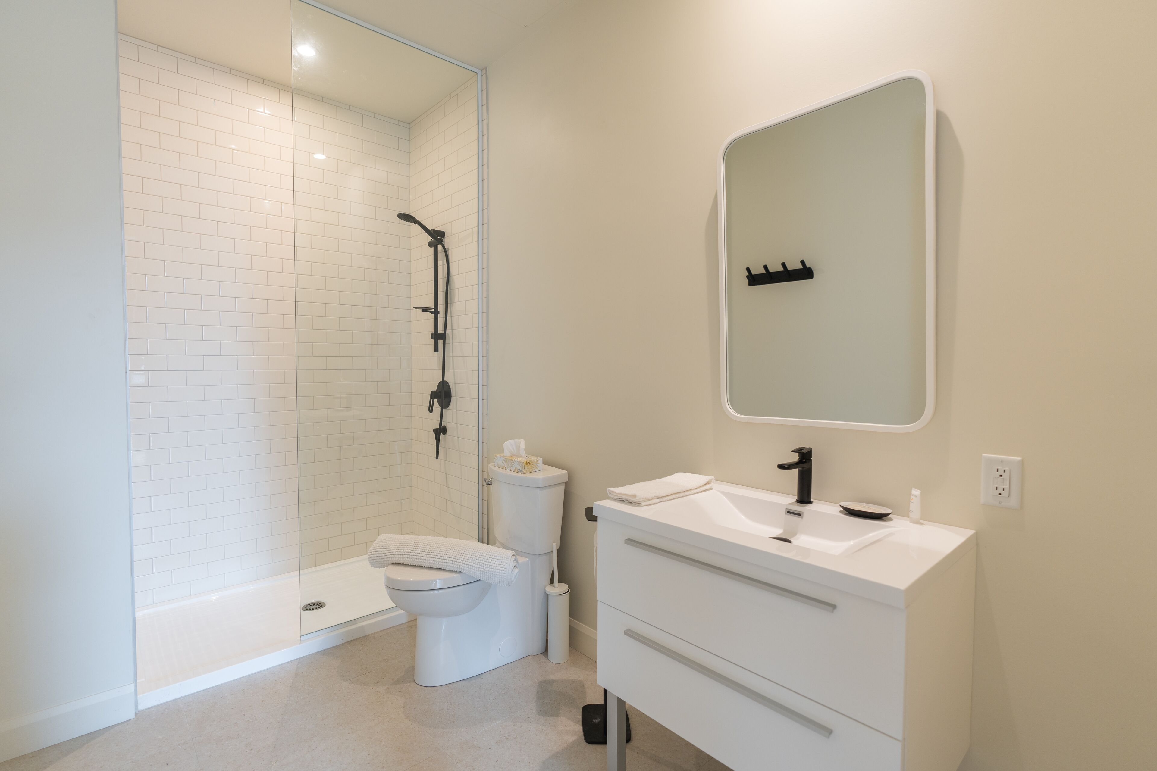 Un baño moderno con ducha de vidrio, inodoro y tocador con espejo.