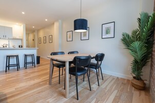 Un comedor moderno con una mesa y sillas de madera, una lámpara colgante y cuadros en las paredes.