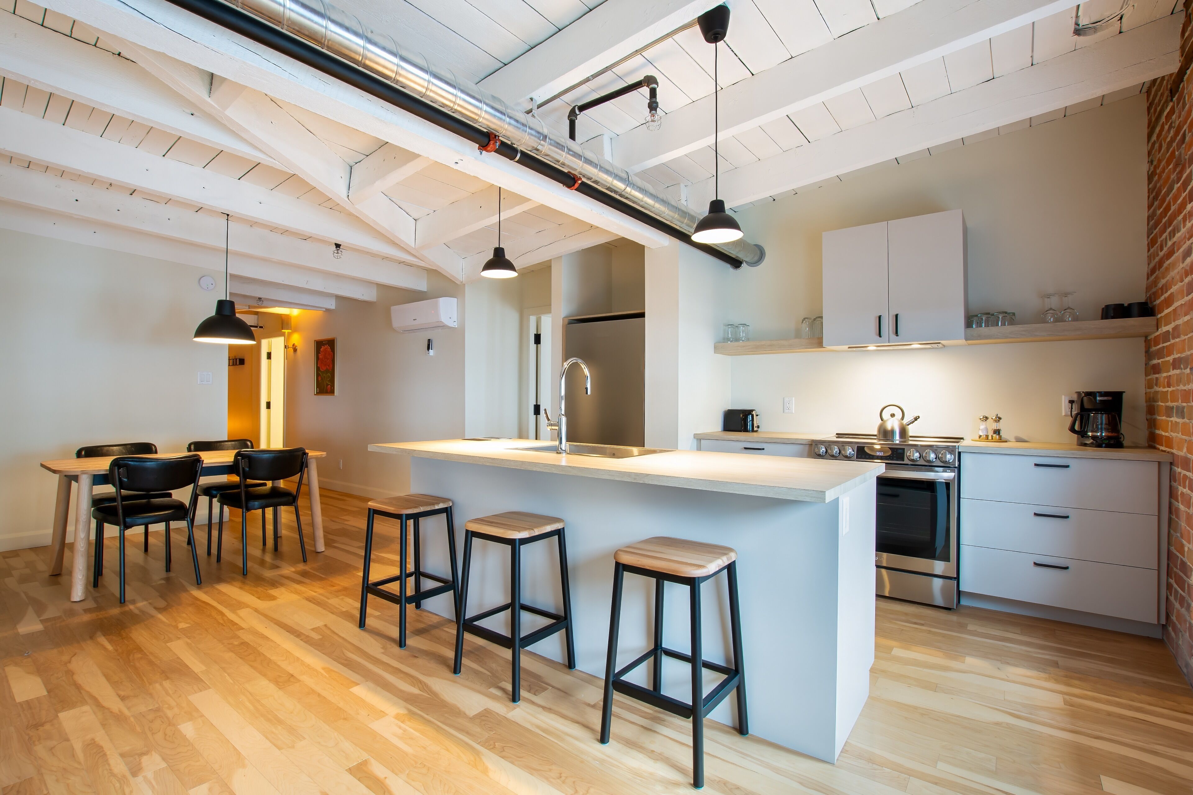 Una cocina moderna con una isla central, taburetes de bar y una zona de comedor con sillas.