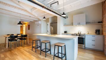 Una cocina moderna con una isla central, taburetes de bar y una zona de comedor con sillas.