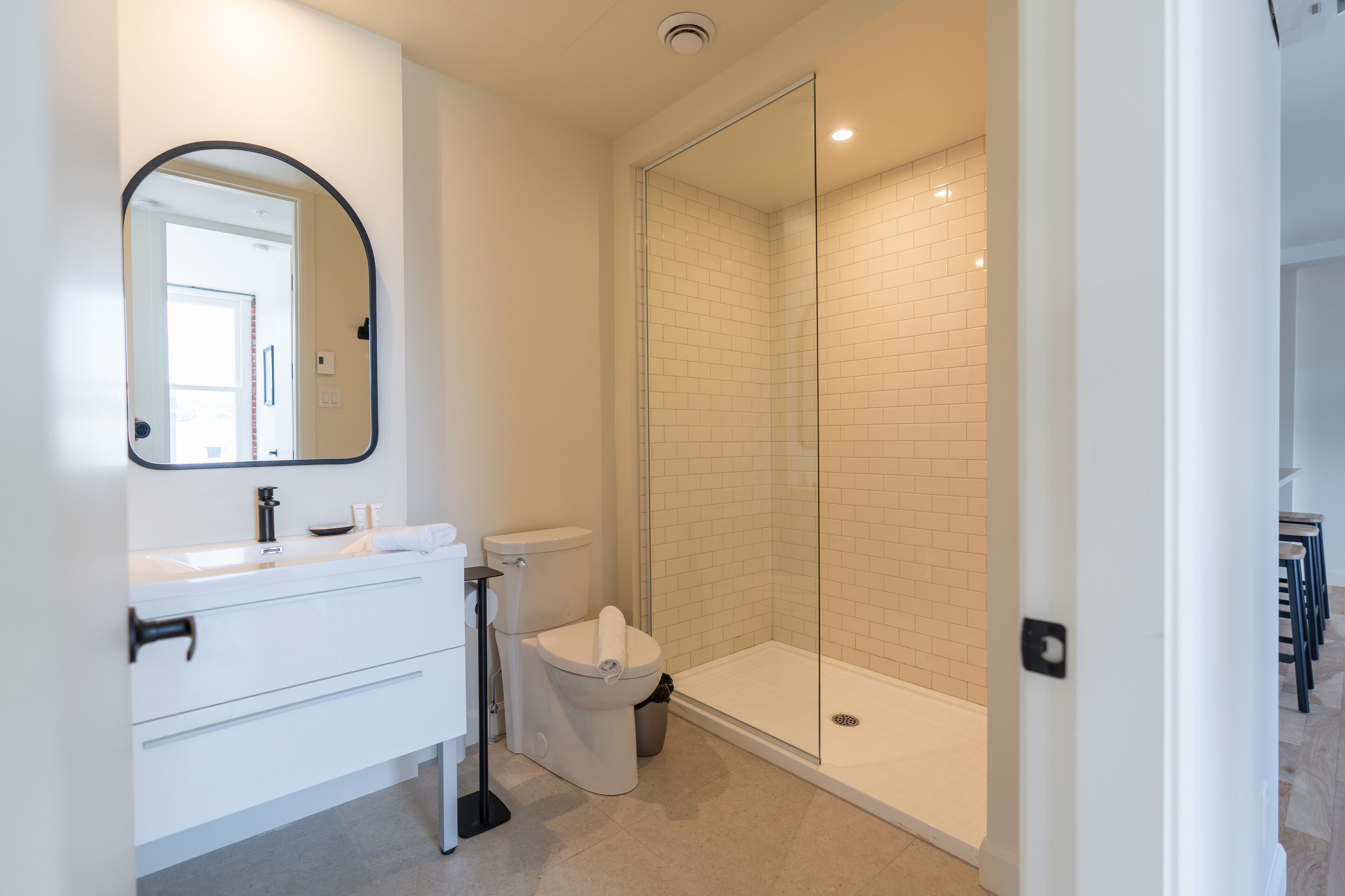 A modern bathroom with a white vanity, a toilet, and a glass-enclosed shower.