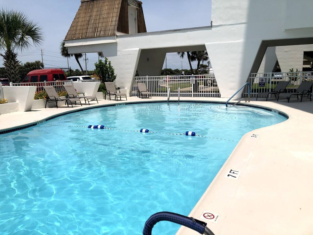 A swimming pool with lounge chairs and a covered area.