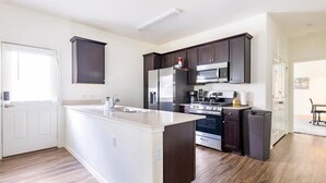 A modern kitchen with dark cabinets, stainless steel appliances, and a large island. - ENTIRE HOME | 3BR WFH Hub | Fast 300 Mbps Wi-Fi | Near SoCo (Austin)