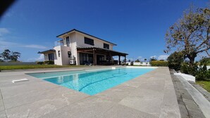 A modern house with a swimming pool, surrounded by a paved patio and greenery. - Jags villa (Union Vale)