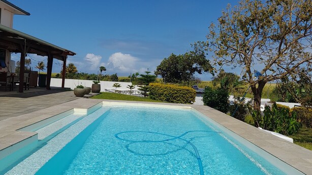 A rectangular swimming pool with clear blue water, surrounded by a tiled deck. - Jags villa (Union Vale)