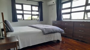 A bedroom with a bed, wooden dresser, and a nightstand. - Jags villa (Union Vale)
