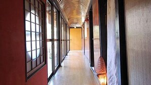 Un pasillo con paneles de madera, ventanas amplias y una puerta de madera al final.
