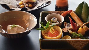 Variedad de platos, incluyendo sashimi, un tazón de sopa y un guiso con verduras y carne.