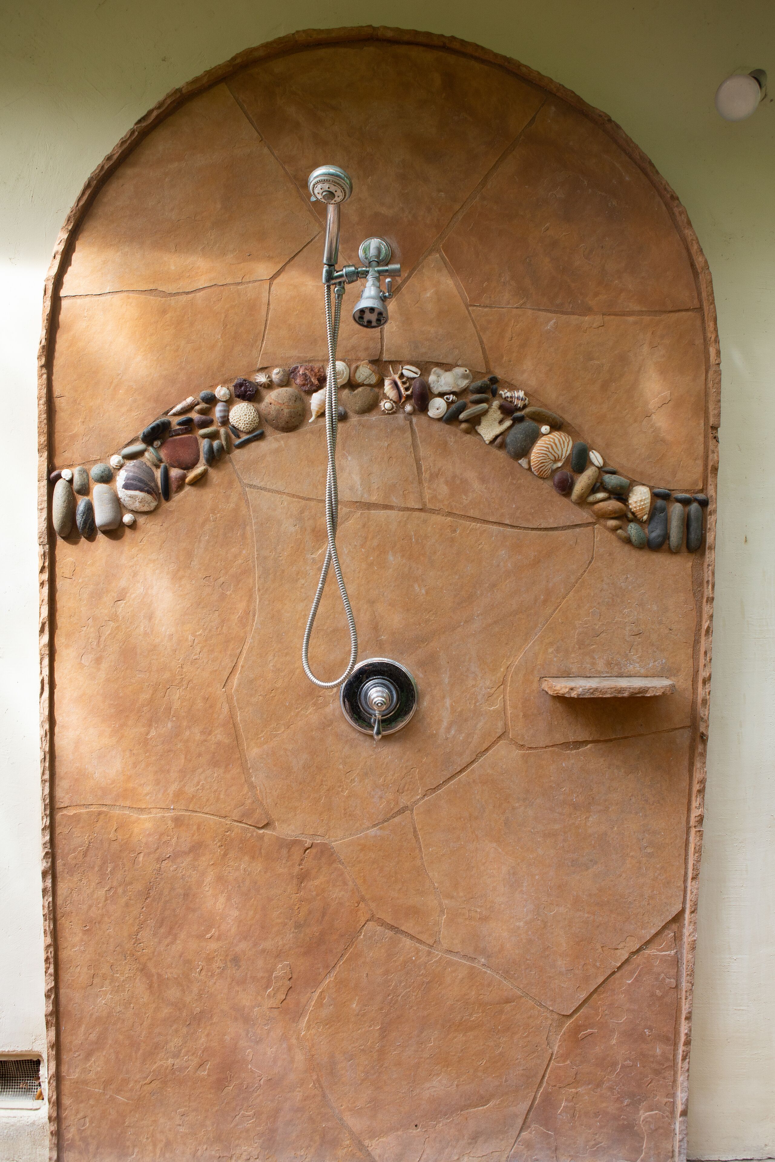 Ducha con diseño de piedra y manguera metálica.