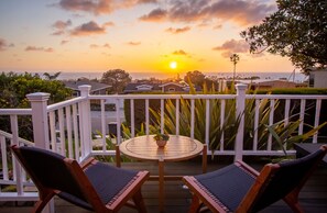 Une terrasse avec deux chaises et une petite table, d’où l’on peut admirer le coucher de soleil sur l’océan.