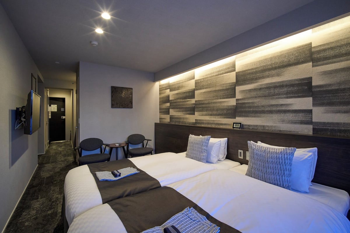 Une chambre d’hôtel dotée d’un grand lit, d’un bureau avec une chaise, d’un téléviseur à écran plat et d’une œuvre d’art accrochée au mur.