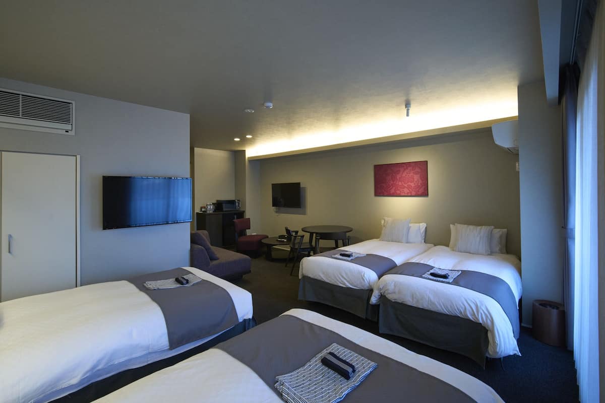 Une chambre d’hôtel avec deux lits, une télévision, un bureau et une chaise.