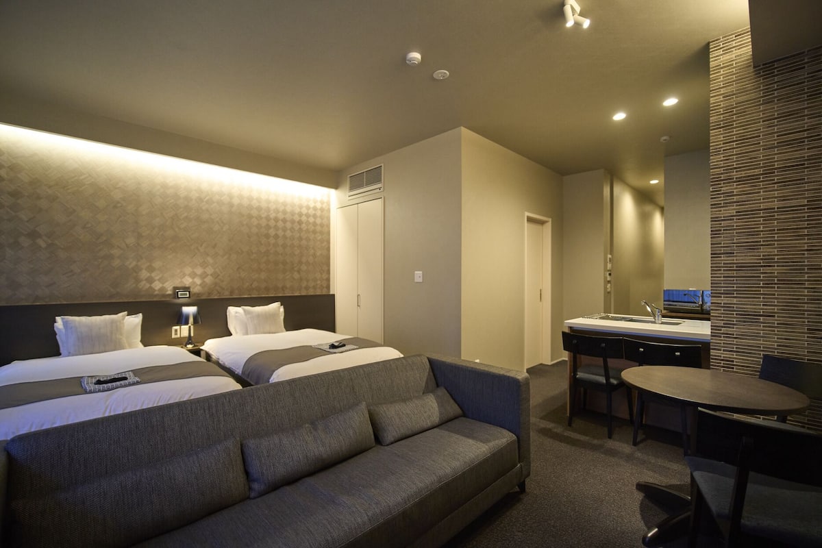 Une chambre d’hôtel moderne avec un grand lit, un canapé, un bureau doté d’un lavabo et un miroir.