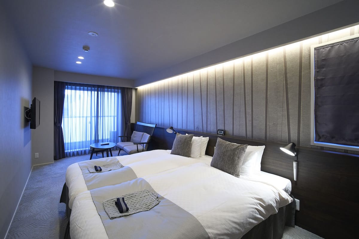 Une chambre d’hôtel moderne, dotée d’un grand lit, d’un bureau et d’une chaise.